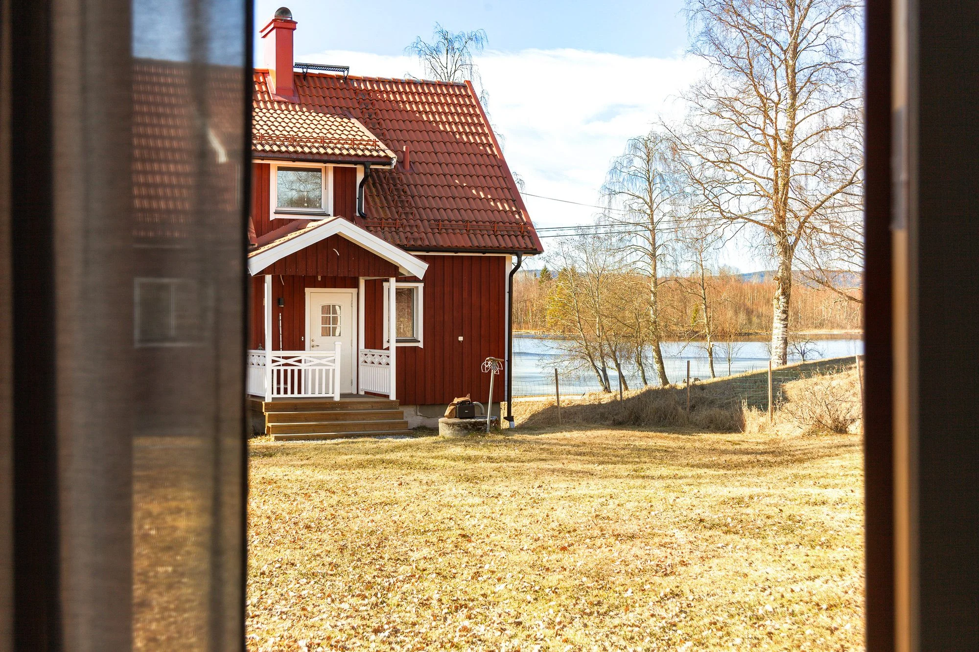 Snyggast i höst 10 Röd stuga vid sjön med kala björkar och gult gräs