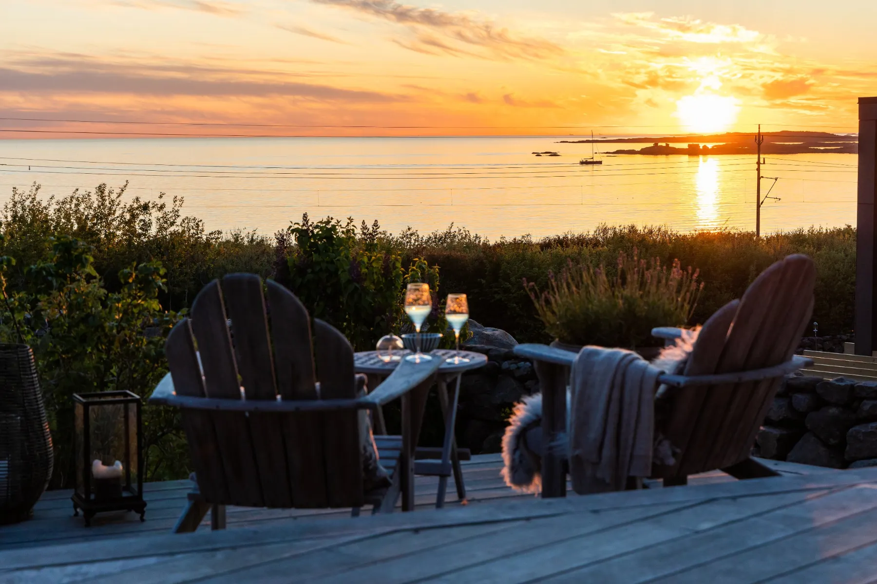 Skymningsfoto 2 Terrass med fällar och lykta i solnedgång över havet